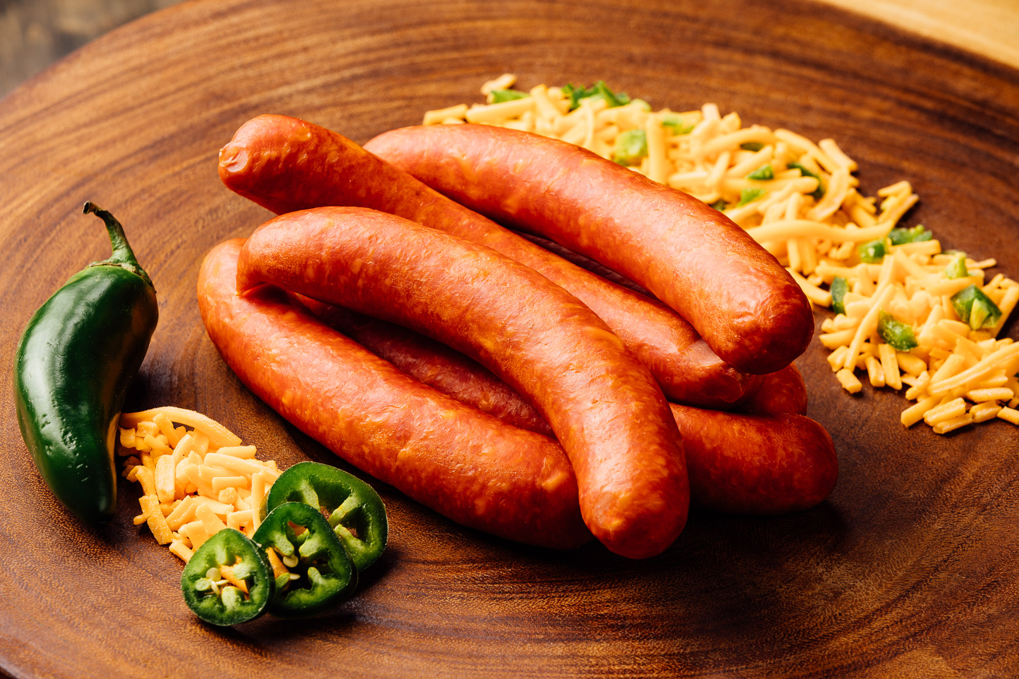 Spicy jalapeño and cheddar paired with smoked pepperoni meat sausages on a wooden board.