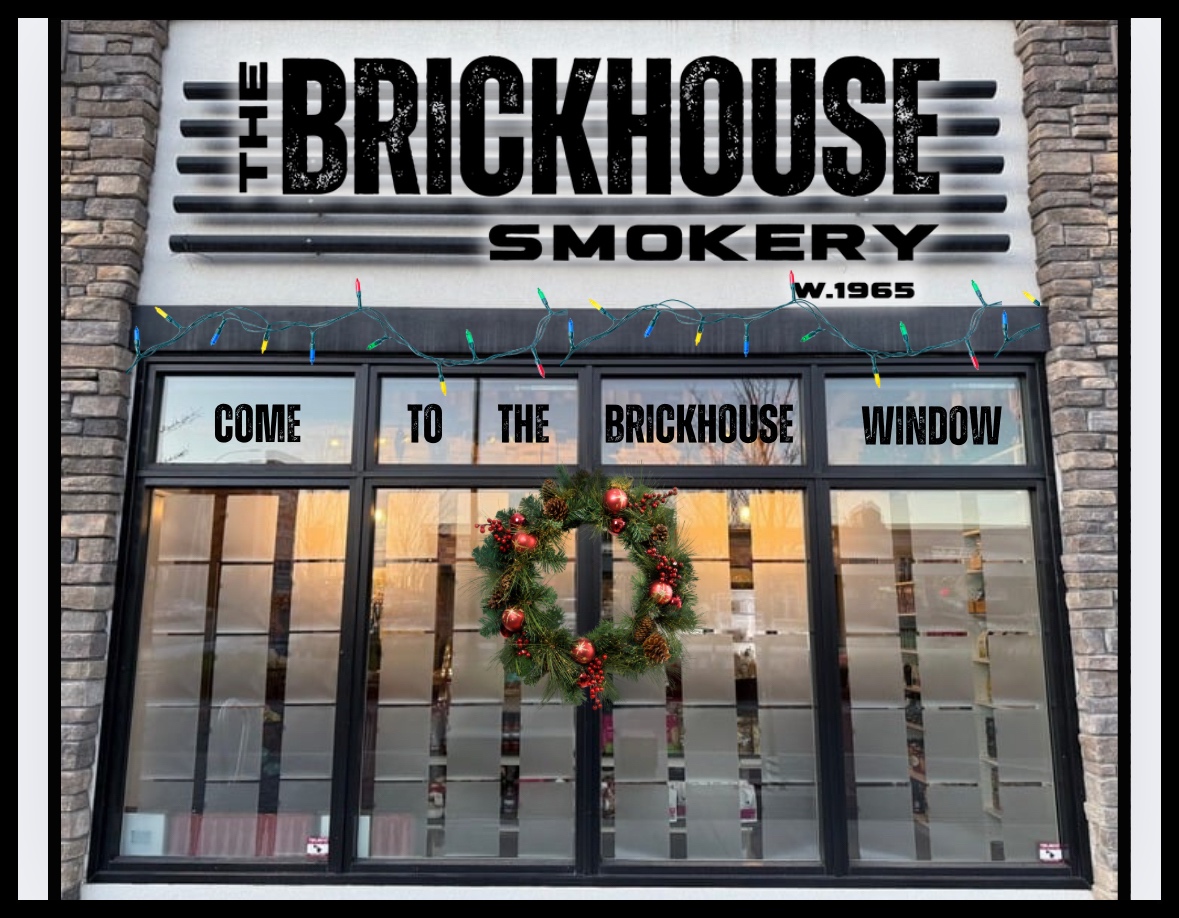 Storefront of The Brickhouse Smokery, decorated with holiday lights and a wreath, inviting customers to visit the window, with a subtle connection to their premium beef jerky box offerings displayed inside.
